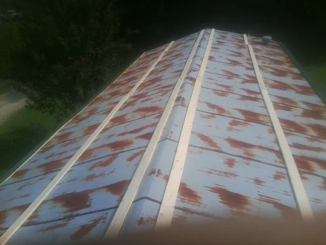 Rusted metal roof panels with new wood purlins before replacement — Storm Damage Roof Repair in Spring Glen by Roofing Brothers