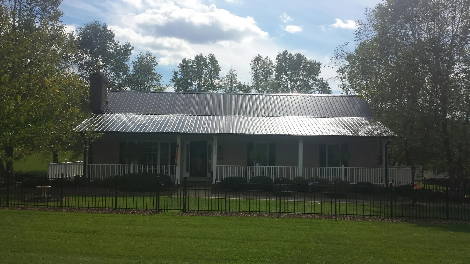 Gray metal roof on a brick ranch with a full width front porch — Gutter Guard Installation work by our crew in Spring Glen