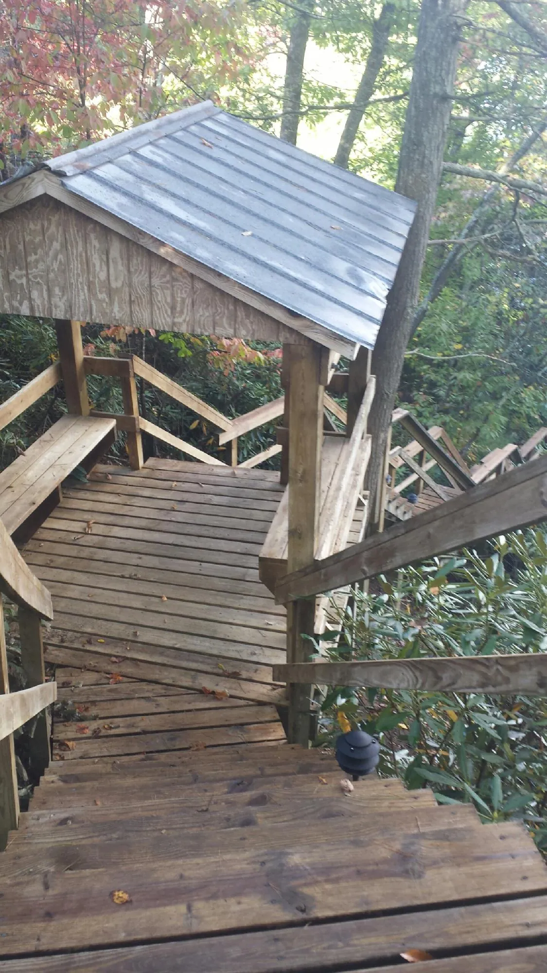 Metal roofed shelter over wooden steps on a wooded walkway — Skylight Repair & Installation work by our crew in Spring Glen